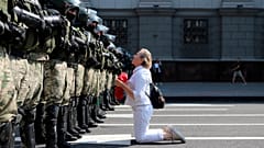 Una donna si inginocchia davanti agli agenti della polizia antisommossa, che blocca la manifestazione dei sostenitori dell'opposizione bielorussa, Minsk