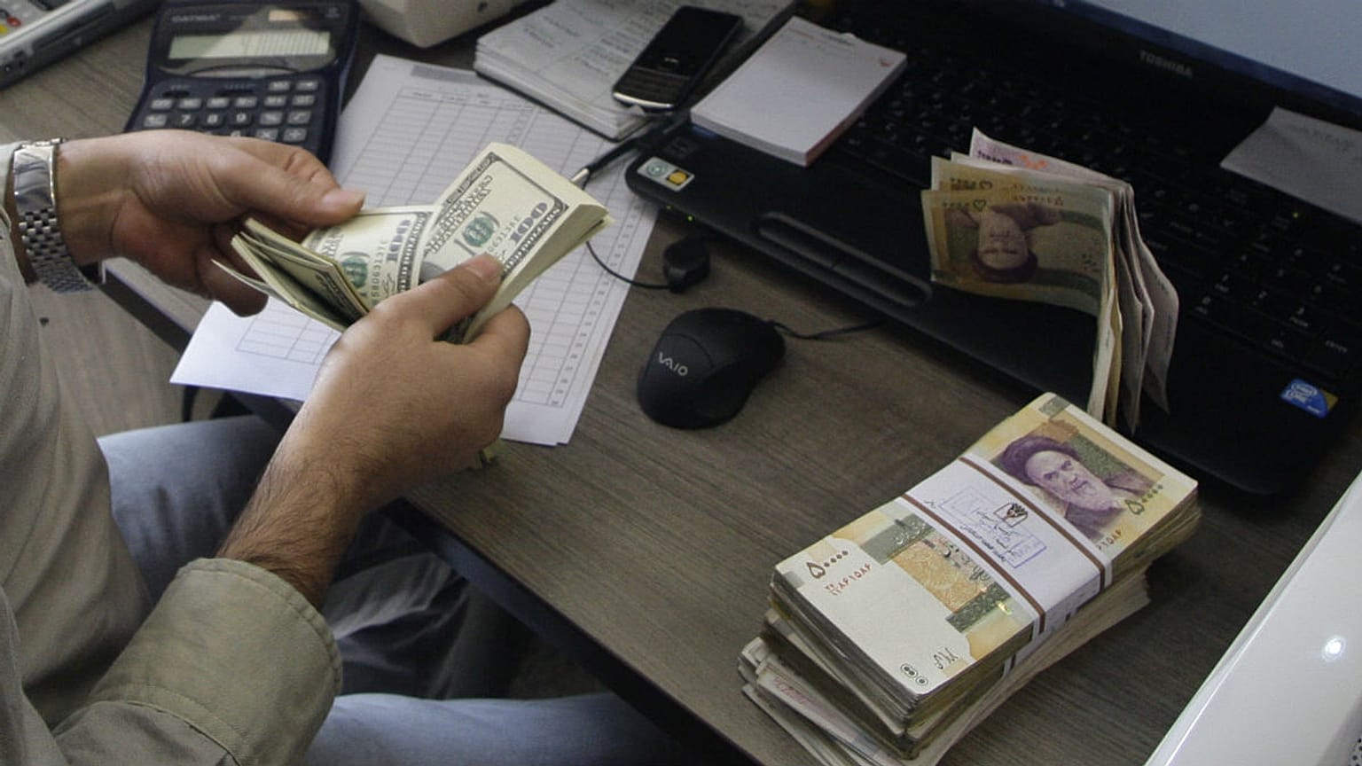 A currency exchange bureau worker counts US dollars,Tehran, Iran