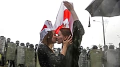 Two women kiss under an old Belarusian national flag as tens of thousands of protesters gather in Minsk