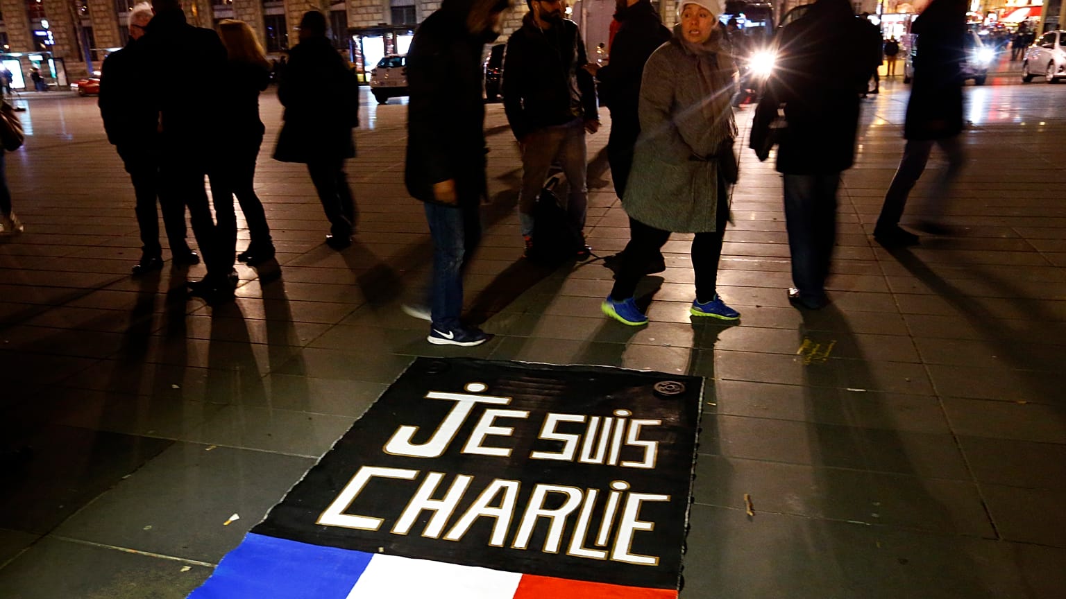 Le persone camminano intorno allo striscione "Je suis Charlie", "Io sono Charlie", in Place de la Republique durante un raduno che segna un anno dagli attacchi a Charlie Hebdo.