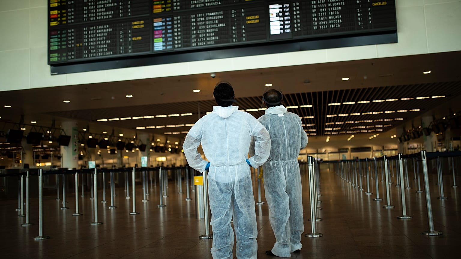 Utasok védőöltözékben a brüsszeli Zaventem repülőtéren