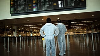 Utasok védőöltözékben a brüsszeli Zaventem repülőtéren
