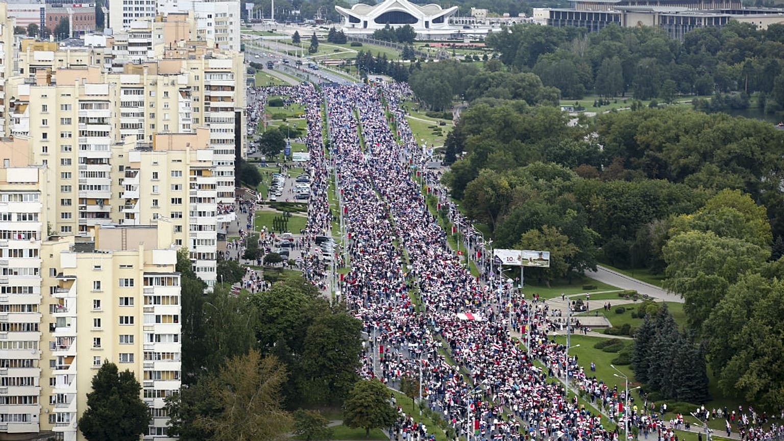 Belarusian opposition supporters with old Belarusian national flags gather toward the Independence Palace, the residential of Belarusian President Alexander Lukashenko in Mins