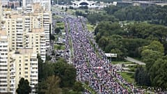 Belarusian opposition supporters with old Belarusian national flags gather toward the Independence Palace, the residential of Belarusian President Alexander Lukashenko in Mins