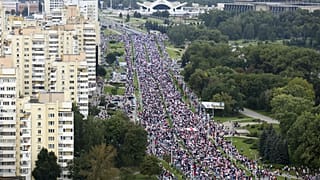 Belarusian opposition supporters with old Belarusian national flags gather toward the Independence Palace, the residential of Belarusian President Alexander Lukashenko in Mins