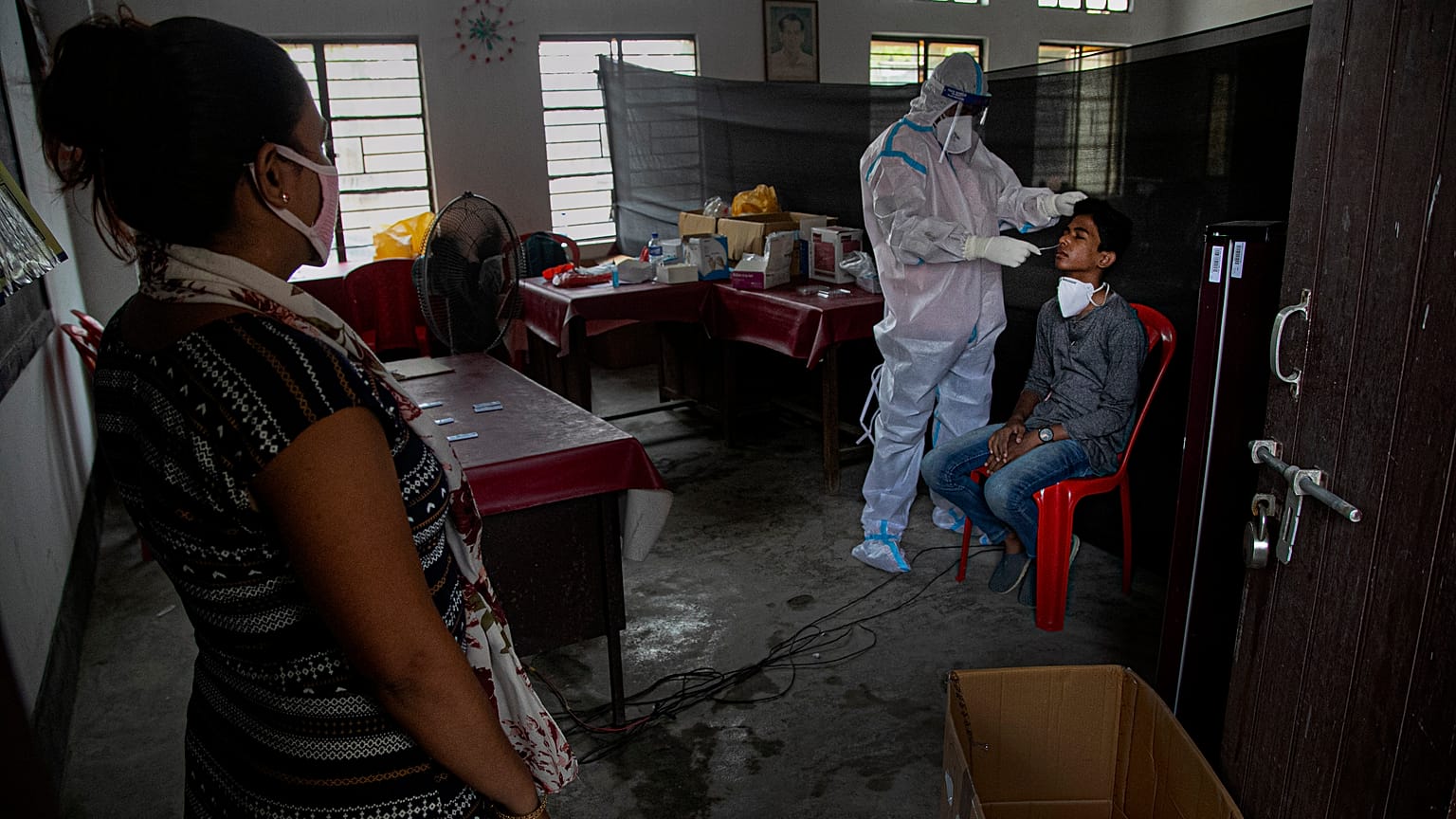 An Indian health worker takes a nasal swab sample of a man to test for COVID-19 as a woman waits for her turn in Gauhati, India, Sunday, Sept. 6, 2020.