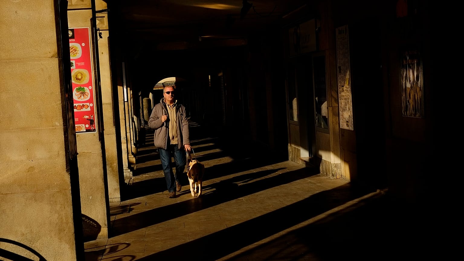 Un hombre invidente pasea con su perro guía por los pórticos de la ciudad vieja durante un día de invierno en Pamplona, en el norte de España. 