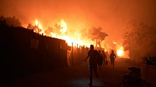 لاجئون ومهاجرون يفرون من مخيم موريا للاجئين في جزيرة ليسبوس اليونانية بعد اندلاع حريق، 9 سبتمبر 2020