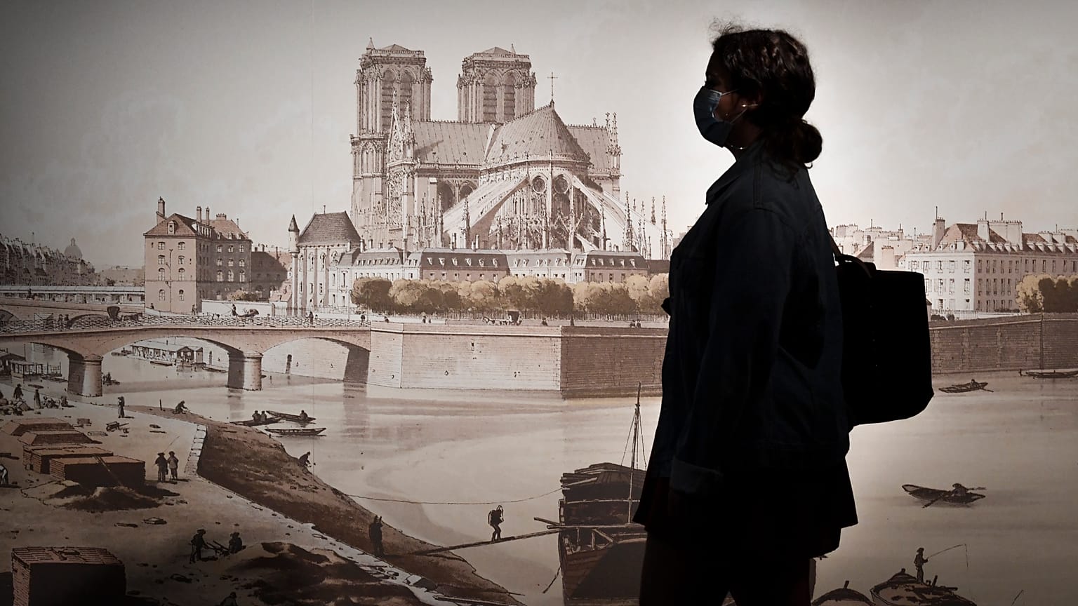 A woman passes by a lithography copy by Feodor Hoffbauer (1839-1922) depicting Notre-Dame Cathedral between 1595 and 1875