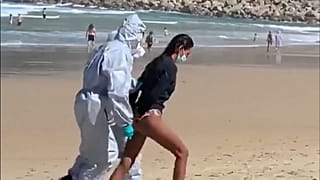 Momento en el que la detenida es sacada de la playa con las manos esposadas en la espalda