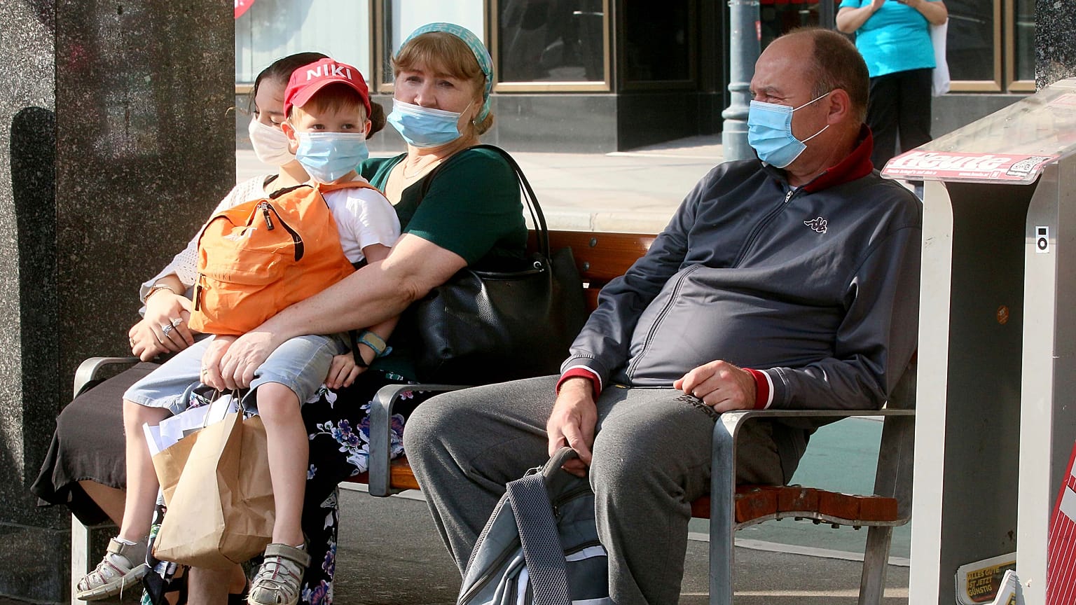 People wear face mask as they sit on a public seat near to the Vienna Opera station, in Vienna, Aug. 13, 2020.