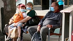People wear face mask as they sit on a public seat near to the Vienna Opera station, in Vienna, Aug. 13, 2020.