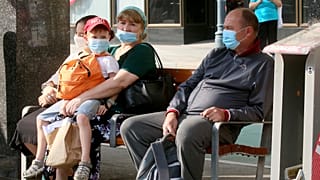 People wear face mask as they sit on a public seat near to the Vienna Opera station, in Vienna, Aug. 13, 2020.