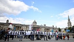 Activists from the climate protest group Extinction Rebellion hold up a banner displaying "Citizens' Assembly is the Answer' in Trafalgar Square in central London.