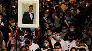 A man holds up a picture of Willy Monteiro Duarte during a torch light procession in Paliano, Italy, on September 9, 2020