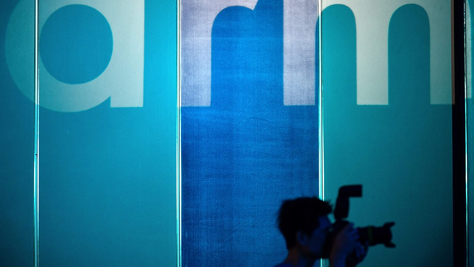 A photographer takes pictures in front of a logo showing the ARM, one of the main chip designer in the world from the UK.
