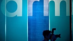 A photographer takes pictures in front of a logo showing the ARM, one of the main chip designer in the world from the UK.