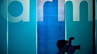 A photographer takes pictures in front of a logo showing the ARM, one of the main chip designer in the world from the UK.