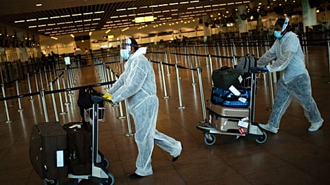 Pasajeros con equipamiento de protección personal completo en el aeropuerto Zaventem de Bruselas