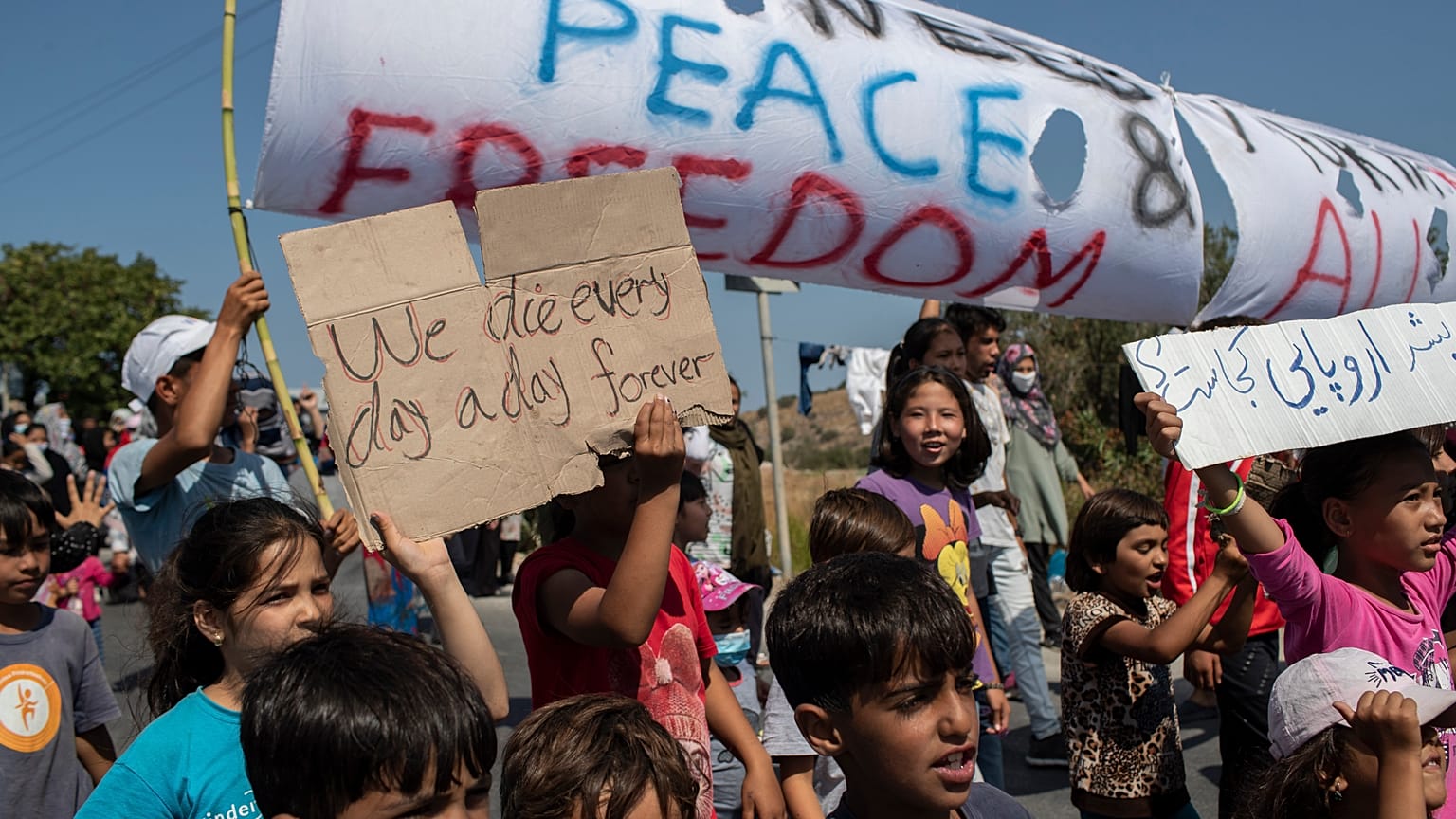 Migrants shout slogans during a protest near Mytilene town, on the northeastern island of Lesbos, Greece, Monday, Sept. 14, 2020. 