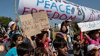 Migrants shout slogans during a protest near Mytilene town, on the northeastern island of Lesbos, Greece, Monday, Sept. 14, 2020.