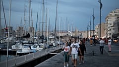 People stroll along Marseille's Old Port, southern France, July 25, 2020. Marseille and Bordeaux are tightening restrictions amid a sharp uptick in coronavirus cases.