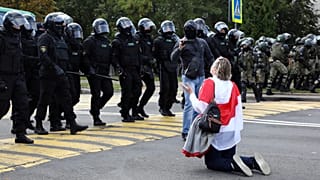 Eine Frau kniet vor Polizeikräften in Minsk während der Proteste