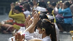 Women wearing face masks as a precaution against the new coronavirus outbreak pray during a Hindu ritual prayer at a temple in Bali, Indonesia