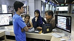  An Iranian shopkeeper talks to his costumers thinking of buying an iPhone in an electronics shop in Tehran, Iran
