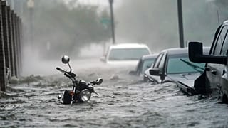 Cars and a motorcycle are underwater as water floods a street, in Pensacola, Fla., Wednesday, Sept. 16, 2020