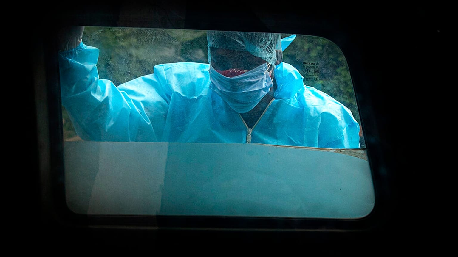 A man wearing personal protective equipment looks at the body of his relative who died of COVID-19 before cremation in Gauhati, India, Thursday, Sept. 10, 2020. 