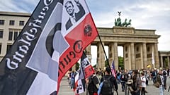 Q für QAnon und ein Portrait von Trump auf rechtsextremer Fahne