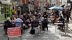 People sit outside on a street closed to traffic to try to reduce the spread of coronavirus in London, Saturday, Sept. 19, 2020.