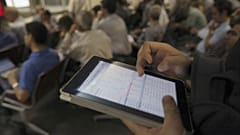An Iranian shareholder monitors shares prices on his tablet at the Tehran Stock Exchange in Tehran, Iran