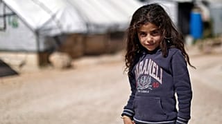 A Syrian girl poses for a picture at a refugee camp in the eastern Lebanese border town of Arsal, Lebanon.