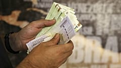 A man counts his banknotes and traveler checks in Tehran, Iran