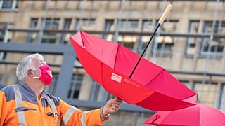 Esernyőt tart a magasba egy tiltakozó a németországi Güterslohban 2020. szeptember 22-én