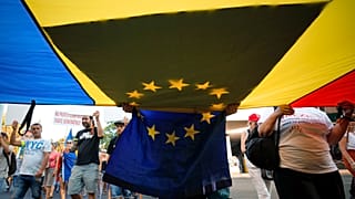 People carry Romanian and European Union flags as they gather for an anti-government protest outside the government headquarters in Bucharest, Romania, August 10, 2019.