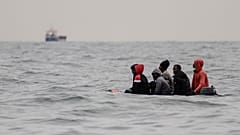 Migrants aboard a boat in rough waters in the English Channel as they attempt to cross to England