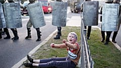 A woman reacts as she sits in front of law enforcement officers during a rally to protest against the presidential inauguration in Minsk on September 23, 2020. 