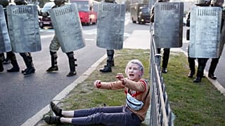 A woman reacts as she sits in front of law enforcement officers during a rally to protest against the presidential inauguration in Minsk on September 23, 2020. 