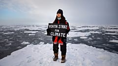 British climate youth activist Mya-Rose Craig standing on ice floe holding a sign reading "Youth Strike for Climate".