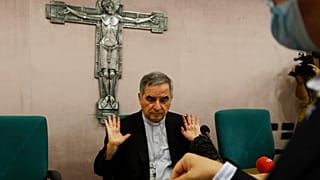 Angelo Becciu talks to journalists on Friday, a day after he resigned and renounced his rights as a cardinal