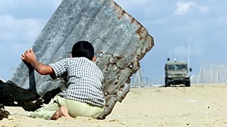 طفل فلسطيني يحتمي خلف لوح حديدي خلال صدامات مع القوات الغسائيلية في غزة - 2000/11/24