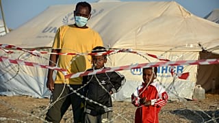 Migrants stand inside the new temporary refugee camp in Kara Tepe, on the northeastern island of Lesbos, Greece