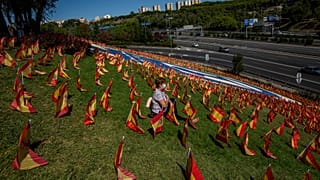Una mujer se sienta entre las banderas españolas colocadas en memoria de las víctimas del coronavirus en Madrid, España, el domingo 27 de septiembre de 2020.