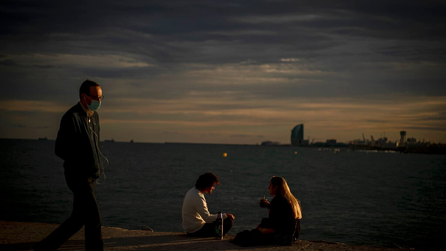 Una pareja y un paseante en el muelle de Barcelona este 27 de septiembre