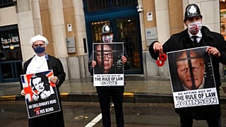 Anti-Brexit protesters hold signs as Michael Gove leaves the third meeting of the EU-UK Joint Committee in Brussels