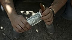 An Iranian street money exchanger holds a U.S. banknote in downtown Tehran, Iran