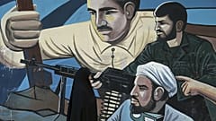 A woman walks past of a mural depicting members of Iran's Basij volunteer paramilitary force, in downtown Tehran, Iran